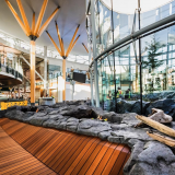Freundliche Atmosphäre im Flughafengebäude innen mit Blick auf Holzinstallationen und durch große Glasfenster und 