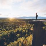 Eine Frau steht auf einem hohen Felsen auf Manitoulin Island und blickt in die Weite über den Wäldern