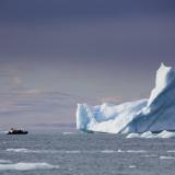 Kleines Boot fährt an einem riesigen Eisberg vorbei