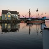 Das Segelschiff „Hector“ passiert bei rosigem Abendhimmel ein Küstenhaus.